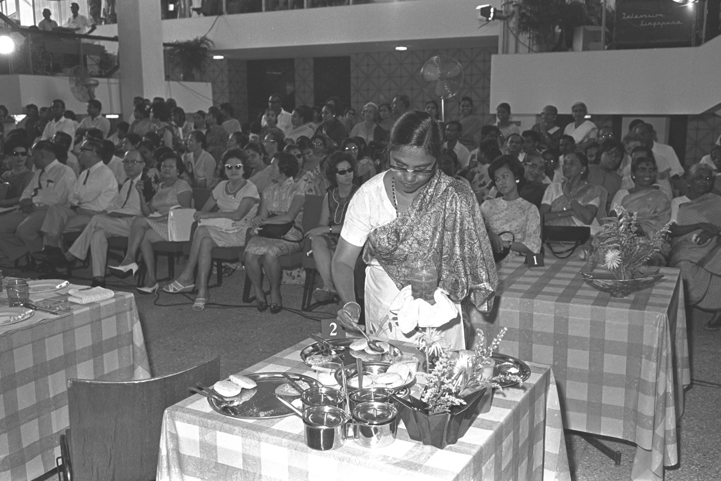A contestant preparing the ingredients to cook at the finals of the nationwide cooking competition held at the Singapore Conference Hall, 1967. Ministry of Information and the Arts Collection, courtesy of National Archives of Singapore.